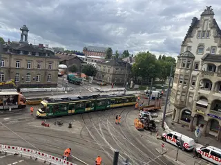 Eine Trambahn passiert bei einer Testfahrt das erneuerte Gleisviereck an der Tullastraße. Im Hintergrund sind das Schlachthof-Areal und das Schloss Gottesaue zu sehen.