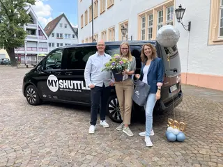 Drei Menschen stehen vor dem KVV.MyShuttle-Bus.