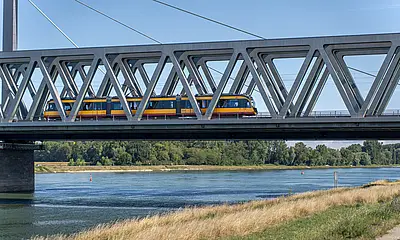 Eine AVG-Stadtbahn überquert die Rheinbrücke bei Maximiliansau.