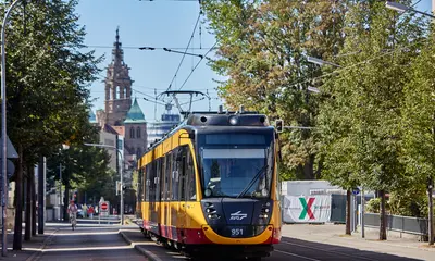 Eine AVG-Stadtbahn fährt durch die Innenstadt von heilbronn. Im Hintergrund ist ein Krichturm zu sehen.