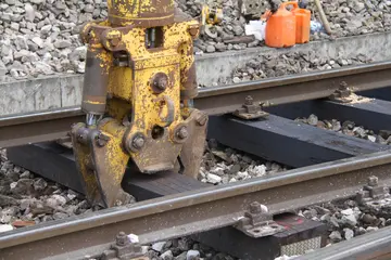 Das Symbolbild zeigt einen gelben Greifbagger, der eine Gleisschwelle anhebt.