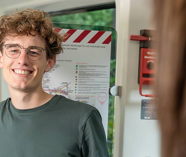 Ein junger Mann steht in der Bahn.