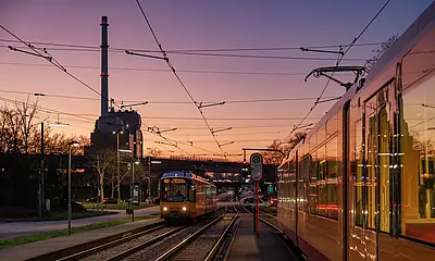 AVG-Stadtbahn fährt bei Sonnenuntergang in der Nähe vom Rheinhafen.