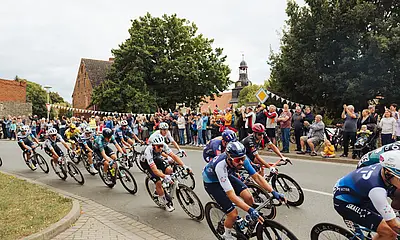 Das Foto zeigt Teilnehmer des Deutschlandtour-Radrennens. Am Streckenrand stehen Zuschauer.