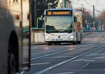 Ein silberfarbener Bus der Linie 62 fährt durch die Stadt. 