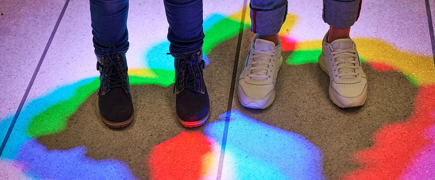 Zwei Paar Füße stehen im Licht von RGB-Lichtspots.