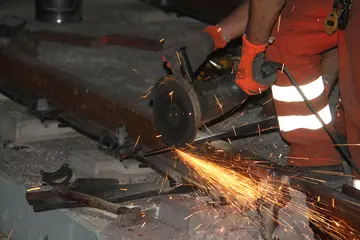 Das Symbolfoto zeigt nächtliche Gleisbauarbeiten. Eine Flex durchtrennt ein Metallstück, Funken sprühen.