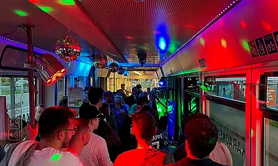 Innenansicht der Karaoke-Bahn mit Menschen und bunten Partylichtern.