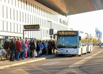 Ein VBK-Bus, der als Messe-Shuttle eingesetzt wird, steht vor der Messe Karlsruhe, an einer Haltestelle. Dort warten offerta-Besucher auf den Einstieg. 