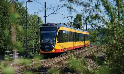 AVG-Stadtbahn fährt auf Gleisen im Umland. 