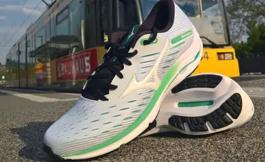 Ein Paar Laufschuhe liegt auf dem Bahnsteig einer Bahnhaltestelle. Im Hintergrund ist eine Straßenbahn zu sehen.