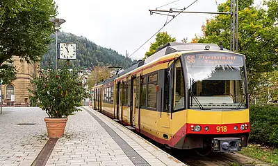 Eine AVG-Stadtbahn steht an der Haltestelle Bad Wildbad Kurpark mit geöffneten Türen. 