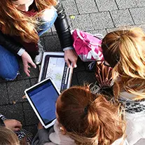 Junge Menschen stehen im Kreis und schauen auf Tablets