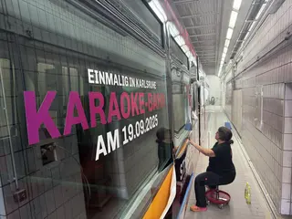 Eine Frau foliert im Betriebshof West im Lackierraum eine VBK-Bahn mit dem Schriftzug: "Einmalig in Karlsruhe. Karaoke-Bahn am 19. September 2025". 