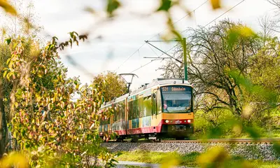 AVG-Stadtbahn fährt durch Landschaft.