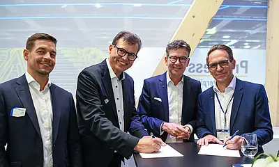 Auf der Innotrans in Berlin haben stehen Männer um einen Tisch. 