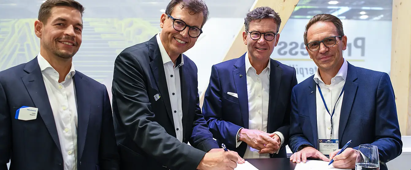 Auf der Innotrans in Berlin haben stehen Männer um einen Tisch. 