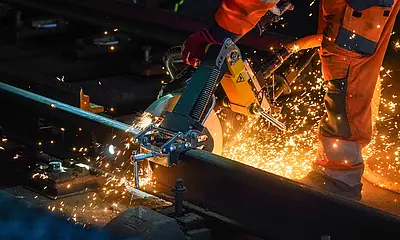 Das Symbolbild zeigt Bauarbeiten am Glas während der Nacht. Funken sprühen. 