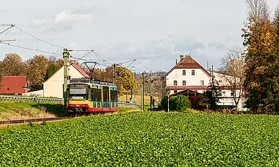AVG-Stadtbahn fährt durch die Landschaft im Kraichtal.