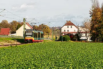 AVG-Stadtbahn fährt durch die Landschaft im Kraichtal.
