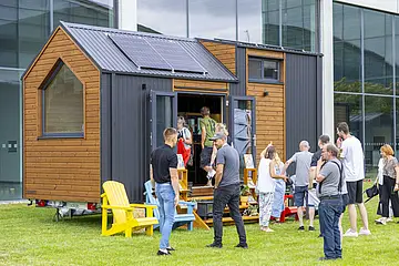 Besucher*innen des Festivals "New Housing" besichtigen ein ausgestelltes Tiny House.
