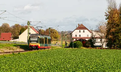 AVG-Bahn fährt durch entlang grüner Landschaft.