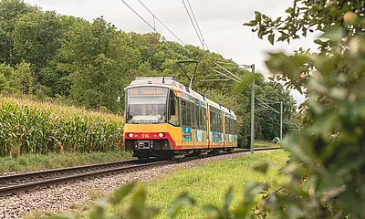 Seitliche Ansicht der AVG-Stadtbahn auf Gleisen.